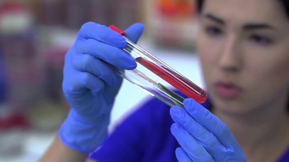Woman Holding Test Tube with Blood Sample in Laboratory
