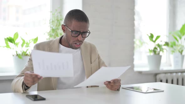 African Man Upset While Reading Documents in Office