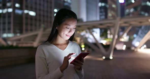 Woman use of mobile phone at business district at night