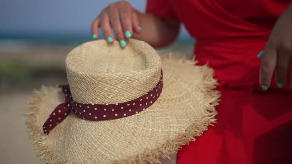 Closeup Straw Hat with Unrecognizable Slim Caucasian Young Woman in Red Dress Sitting on Bench