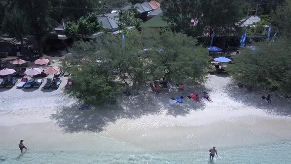 Shady place under a tree on the beachGorgeous aerial view flight fly from up to down crane drone fo