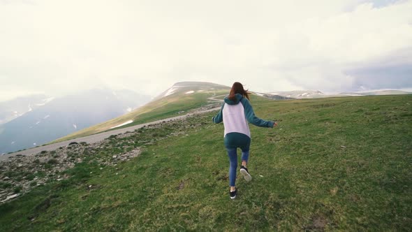 A Young Woman Hiker Running and Spinning on Top of a Mountain