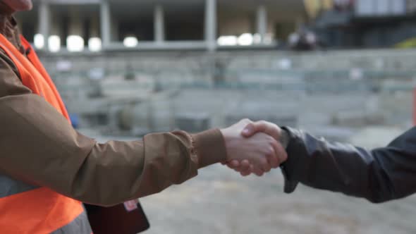 Friendly handshake of two builders at a construction site