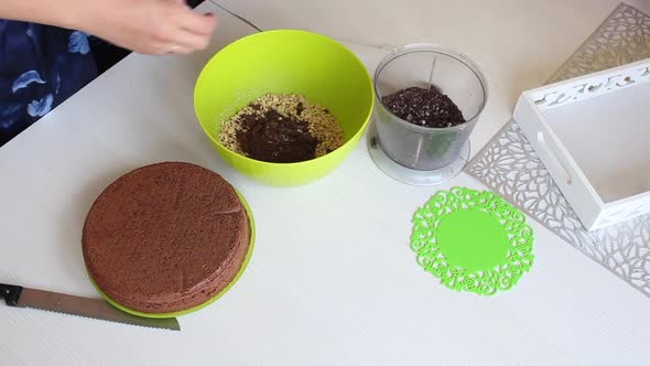 The Woman Adds Peanuts And Chocolate To The Container.