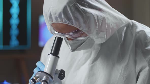 Asian Doctor In Protective Suit Examining Chemical Test Using Microscope