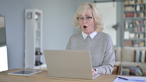 Sad Old Woman Facing Loss on Laptop in Modern Office