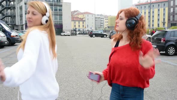 Two friends girl dancing and listening music outdoor