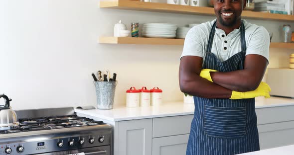 Smiling man standing with arms crossed in kitchen