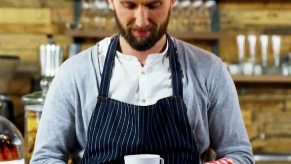 Smiling waiter holding cup of coffee