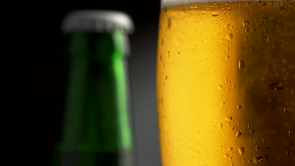 Beer Bottle and Glass of Cold Light Beer Rotation Around Its Axis. Dark Background, 