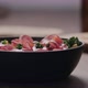 Slow Motion Capers Fall on Salad with Kale Coppa and Cherry Tomatoes in Black Bowl on Concrete - VideoHive Item for Sale