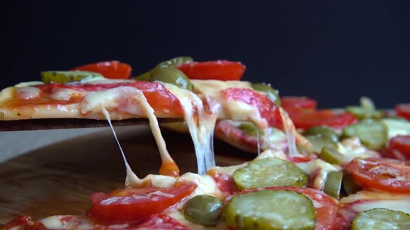 Slice pizza with mozzarella cheese, olives, pickled cucumbers, tomatoes and salami.