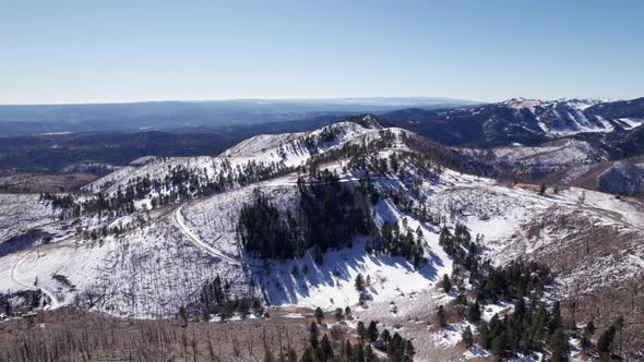 Drone shot looking down on a winding mountain road in the winter