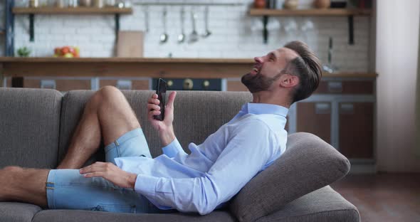 Millennial Bearded Man Saying Wow and Making Yes Gesture While Looking at Smartphone Screen