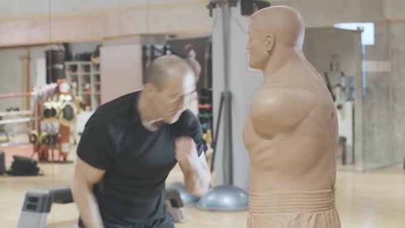 Persistent Caucasian Sportsman Training with Mannequin in Sports Club. Side View Portrait of Adult