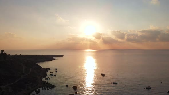 Aerial drone shot rising over Konnos Bay coast with golden sunset.mp4