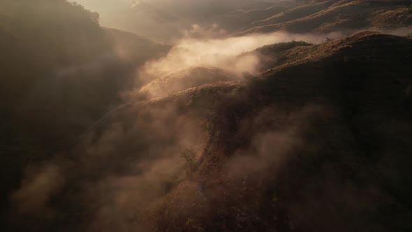 4K Aerial view from drone over mountains fog. Golden scenery at sunrise