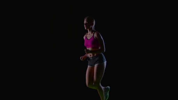 Athletic Fitness Woman Running Front View on a Black Background. Silhouette. Slow Motion