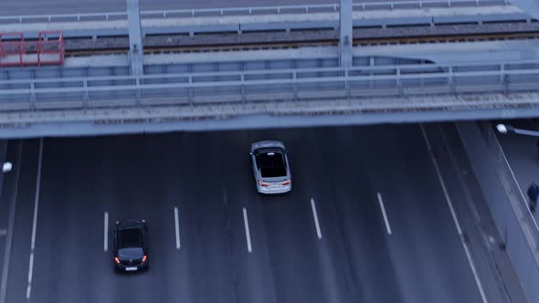 Drone view of white car drives under the American bridge.