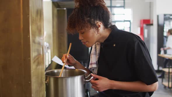 Mixed race female chef cooking dish in a pot