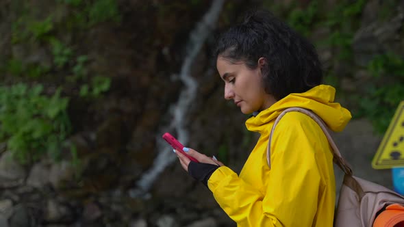 Woman is Using App with Map in Smartphone for Navigating in Natural Reserve Park