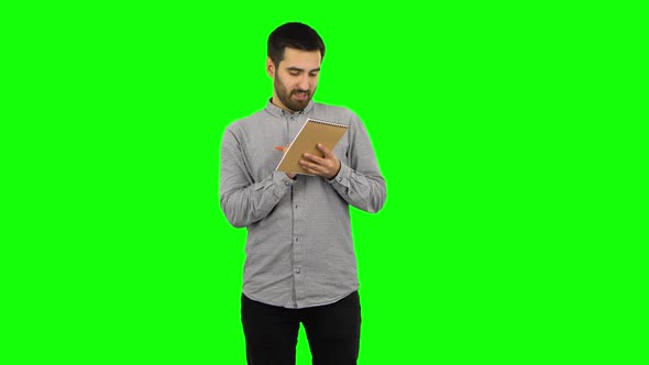 Brunette Guy Is Thinking, Then Writing with Pencil in Notebook. Green Screen