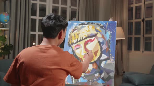 Asian Artist Boy Holding Paintbrush Mixed Colour And Painting A Girl's Hair On The Canvas