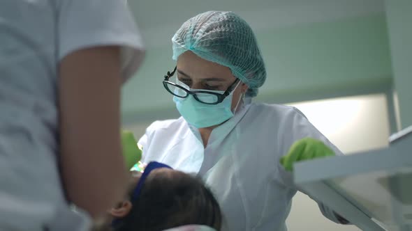 Portrait of Focused Professional Caucasian Female Dentist Working in Hospital Indoors with Patient