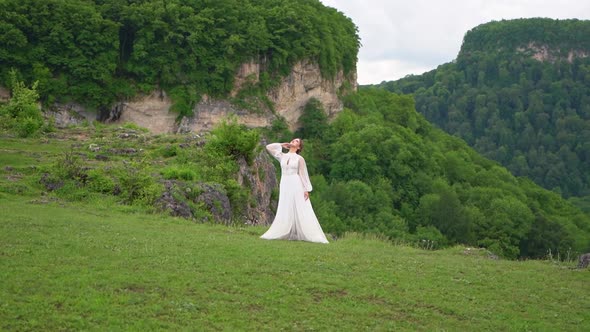 A Young Woman in a Wedding Dress and Black Boots Posing in the Mountains