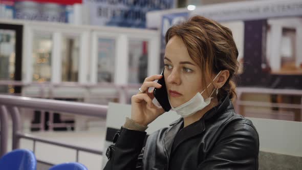 A Business Woman in a Protective Mask Communicates in a Shopping Center