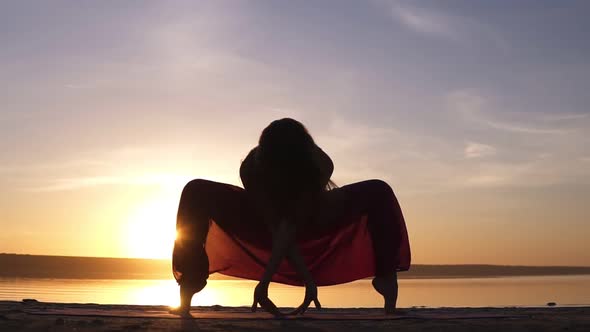 Silhouette Yoga Woman Practicing Upaveshasana on Sea Coast at Beautiful Sunset