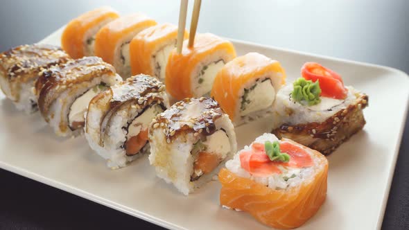 Close-up Eating Sushi on a Rectangular Plate with Chopsticks.