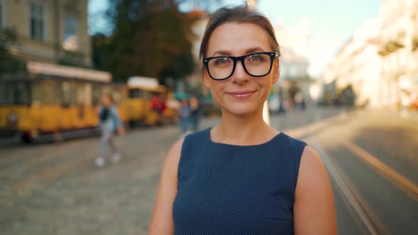 Portrait of a Woman with Glasses Standing in the Middle of a City Square