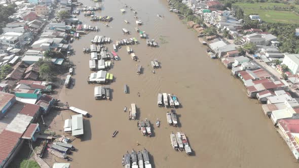 Aerial: flying over Cai Rang floating market in the morning, boats selling wholesale fruits and good