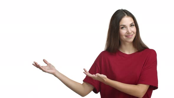 Young Pretty Woman in Red Tshirt Demonstrating Product Pointing Left at Empty White Space for your