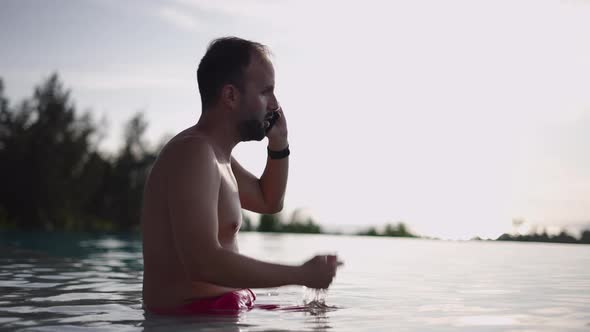 A Middleaged Bearded Man Having a Serious Arguing Phone Conversation Staying Shitless in a Swimming