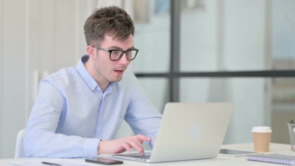 Successful Young Man Celebrating on Laptop at Work