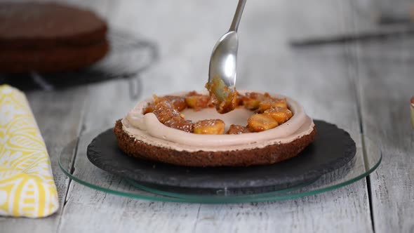 A confectioner puts caramelized bananas on a cake. Process of cooking chocolate sponge cake.	