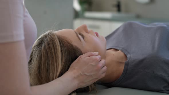 Female physical therapist massaging her patient around head and neck. Shot with RED helium camera in