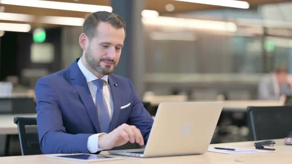 Middle Aged Businessman with Laptop Smiling at Camera