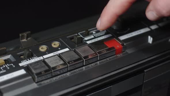 A Man's Hand with a Finger Presses the Play Button on an Old Vintage Gray Cassette Tape Recorder