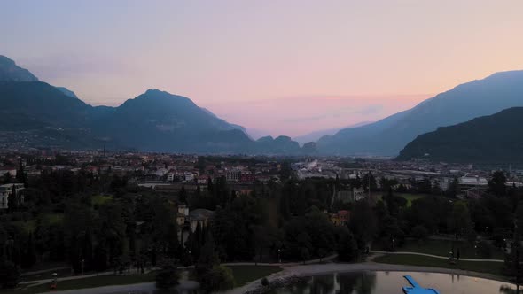 Aerial view of Riva del Garda at sunrise. City overview with mountains and pink sky. Shooting in 4k