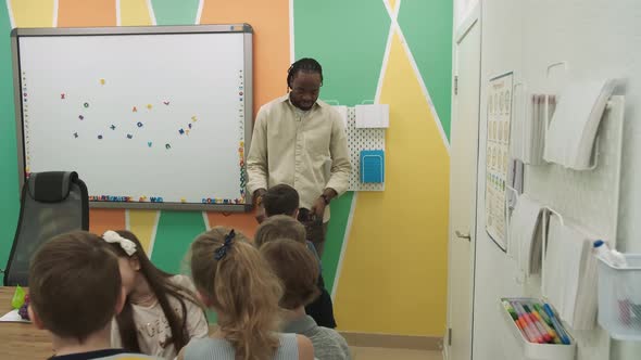 An African American Teacher Teaches a Group of Children 1012 Years Old Studying Animals and Fruits