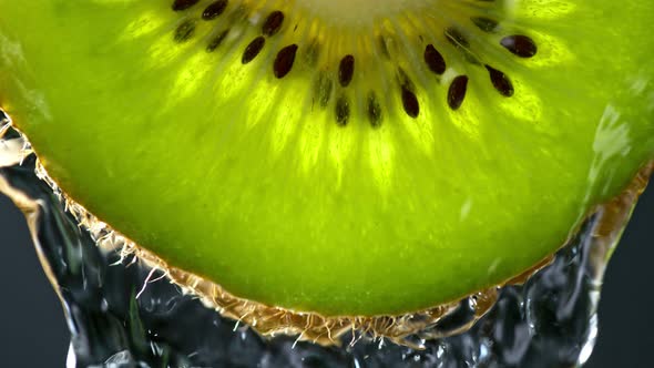 Super Slow Motion Macro Shot of Flowing Water From Kiwi Slice on Black Background at 1000Fps