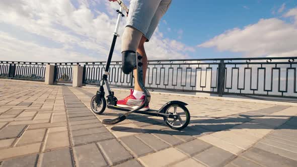 Slow Motion of a Man with Prosthetic Leg Riding a Scooter