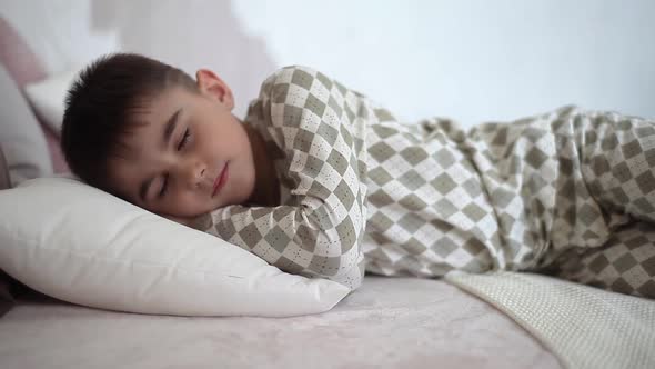 A Little Boy in Pajamas Sleeps on the Bed