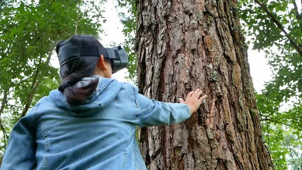 Happy woman wearing VR-headset glasses of virtual reality in forest and enjoying the nature.