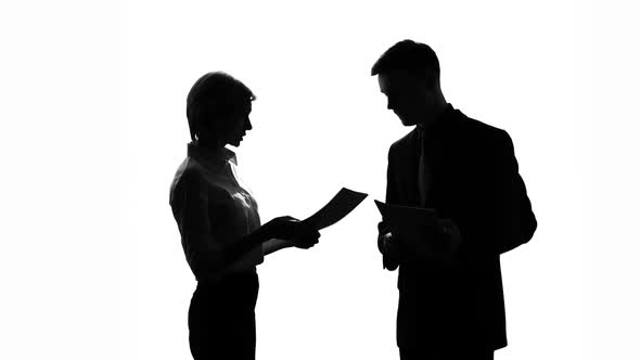 Male and Female Colleague Silhouettes Arguing Over Business Documents at Office