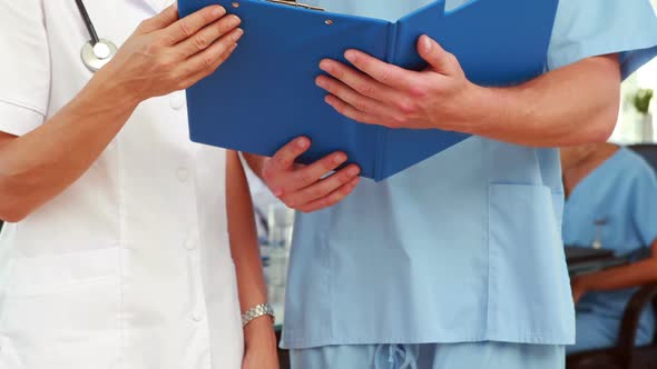 Two doctors holding clipboard in medical office