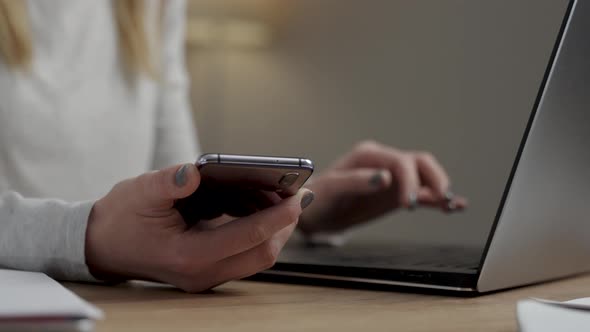 Close up view of the young caucasian woman sitting at the desk with laptop, typing an email